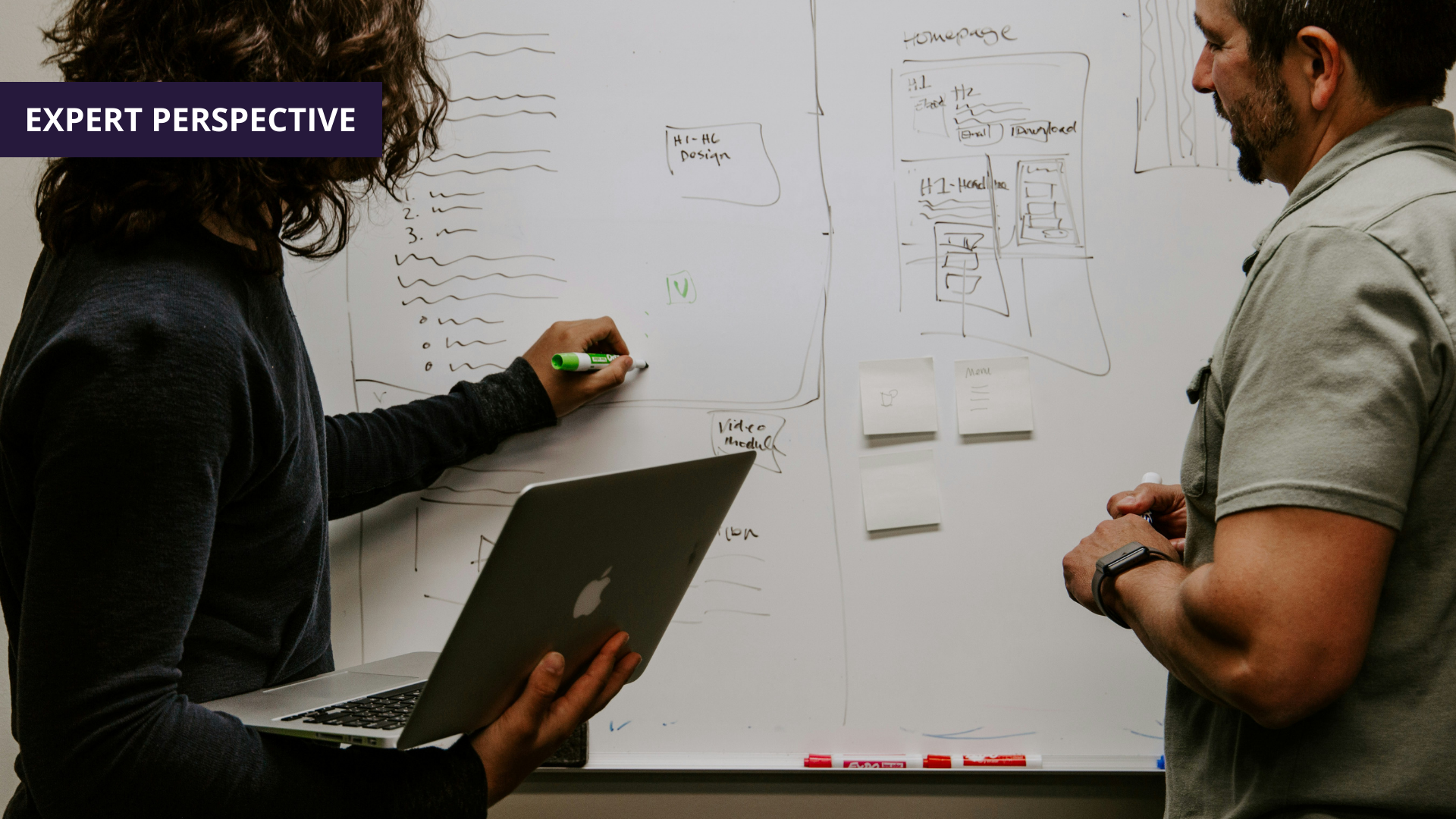 two people discussing plans at a whiteboard