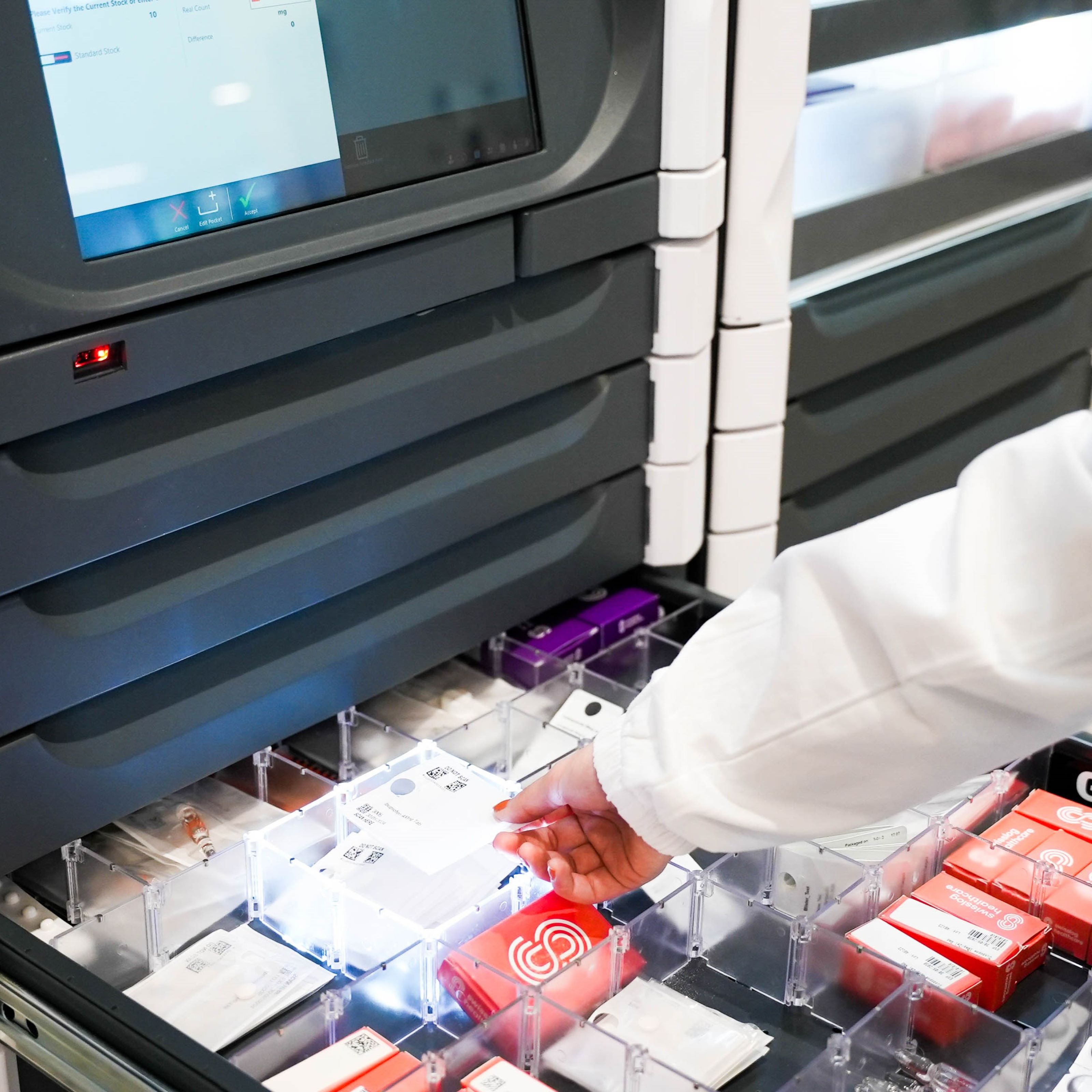 Hand takes unit dose out of MedSMART